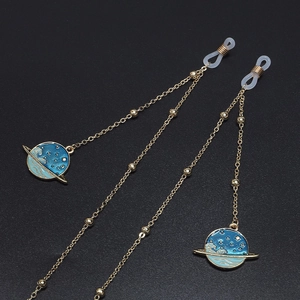 Golden planet eyewear chain with blue enamel charms and star patterns on black surface