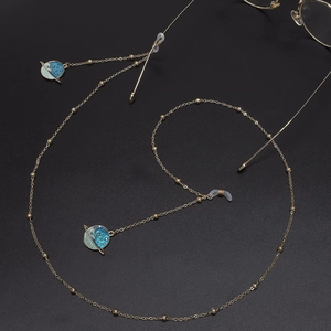 Golden eyewear chain with blue planet enamel pendants on a minimalist black background