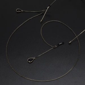 Elegant gold chain eyewear strap with black crystal teardrop pendants on dark background
