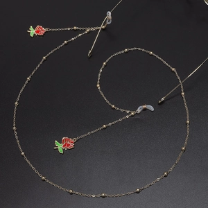 Gold metal glasses chain with red rose charms and beads on a sleek black background