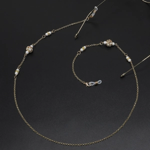 Golden eyewear chain with white pearls and sparkling rhinestone hollow spheres on black base