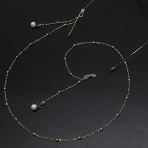 Goldene Brillenkette mit Metallperlen und weißen Perlen auf schwarzem Grund