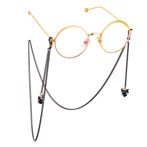 Fashionable gold round glasses with black chain and crystal bow pendant on white background