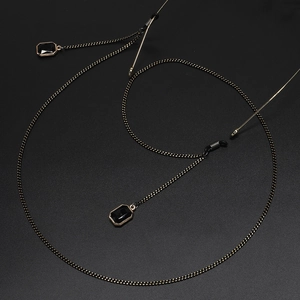 Elegant gold and black eyeglasses chain with rectangular crystal pendants on black background
