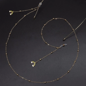 Chaîne de lunettes dorée avec perles et pendentif arc-en-ciel sur un fond noir mat