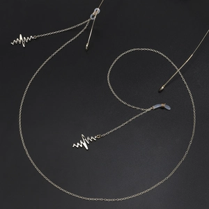 Chaîne de lunettes dorée élégante avec pendentifs battement de cœur sur fond noir