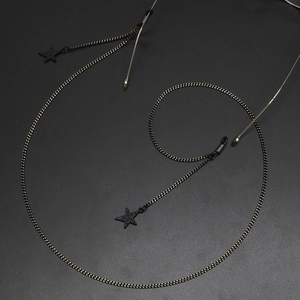Fashionable gold and black eyewear chain with black star charms on a dark textured surface