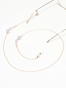 Detail of elegant gold eyeglass chain with gradient pearls and silicone loops