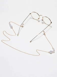 Detail of high-gloss pearl glasses chain with gold metal links on white background