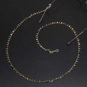 Handmade beaded eyewear chain with colorful stones and gold metal links on black background