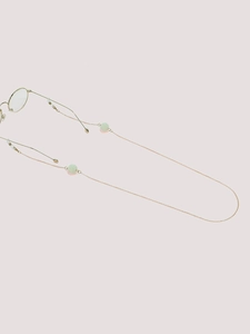 Detail of rose gold metal eyewear chain with pale green beads on a pink background