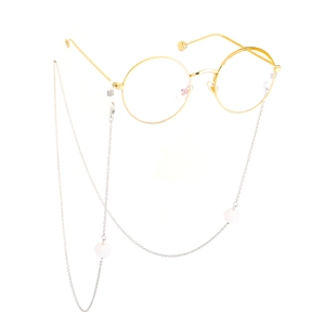 Detail of gold metal round frame glasses with silver beaded chain and white pearls