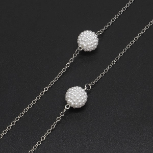 Silver metal eyeglass chain featuring white faux pearl beads on a black background