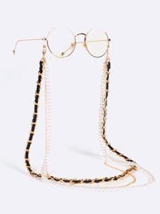 Detail of layered eyewear chain with black leather, white pearls, and gold-tone fringe