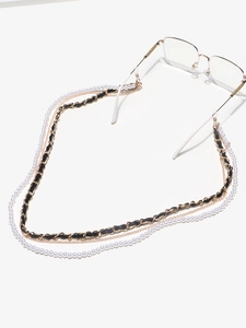 Detail of multilayer eyewear chain with pearls, gold links and black leather woven strap