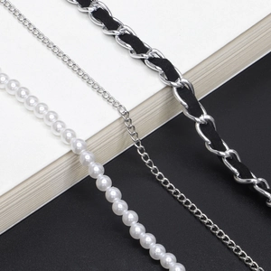 Detail of white pearl chain and black leather woven metal strap for glasses