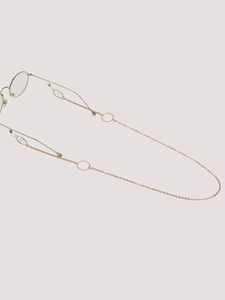 Detail of a golden metal eyewear chain with geometric rings and clear silicone ends