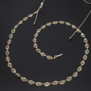 Elegant gold hollow chain link eyewear retainer with rubber loops on a dark textured surface