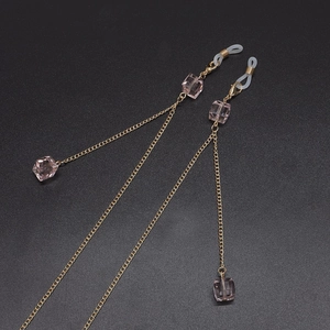 Chaîne à lunettes rétro dorée avec perles de cristal rose sur fond noir texturé