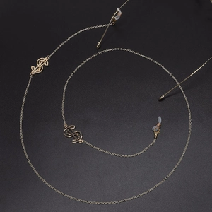 Golden eyewear chain with dollar sign charms and non-slip silicone loops on black background