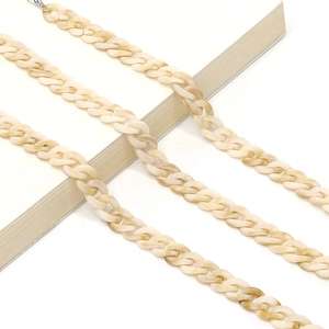 Detailed view of beige marble acrylic eyeglass chain links on a white book surface