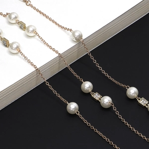 Elegant gold pearl necklace with rhinestone squares, styled as sweater or glasses chain