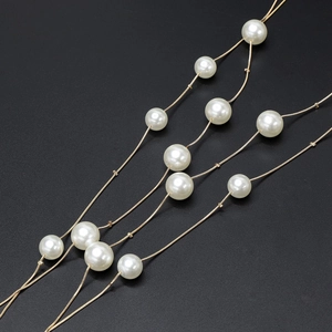 Detail shot of multi-layered golden snake chain necklace with elegant white pearls
