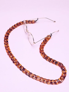 Detail of tortoiseshell acrylic glasses chain with large links on purple background
