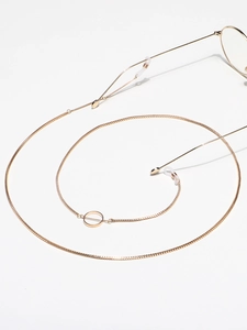 Detail of golden box chain eyewear strap with geometric ring and silicone loops