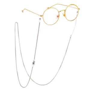 Detail of round gold metal eyeglass frames with silver box chain holder strap