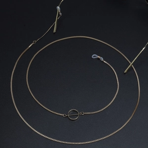 Minimalist gold block chain eyewear strap with round geometric pendant on black background