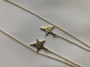 Close-up of golden star necklaces with a unique hammered texture on the pendant surface
