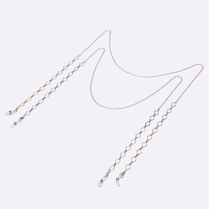 Détail de chaînes de lunettes en métal or rose et argent avec ornements en losange