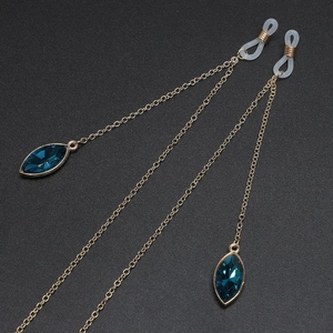Golden metal eyewear chain with dark blue marquise crystal pendants on black background