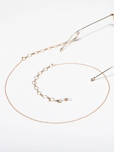 Detail of golden metal glasses chain featuring geometric links and adjustable silicone loops