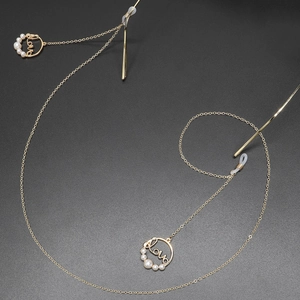 Chaîne de lunettes dorée avec pendentif Love et perles sur fond noir texturé