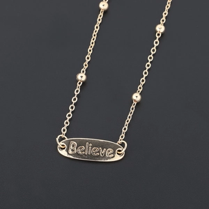 Golden eyewear chain with metal beads and an oval pendant engraved with the word Believe