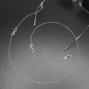 Golden eyewear chain with infinity symbols on a textured grey background with sunglasses