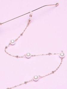 Close-up of rose gold metal eyewear chain with white pearls on a light purple background