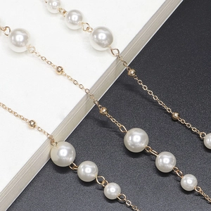Elegant gold pearl glasses chain and necklace with white pearls on a minimalist background