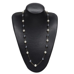 Long gold necklace with alternating white and grey pearls on a black display stand