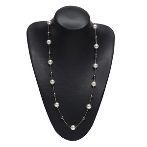 Collier élégant en chaîne dorée avec perles blanches et grises sur un présentoir