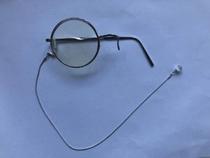 Detail of vintage silver monocle with a round metal frame and delicate pearl beaded chain