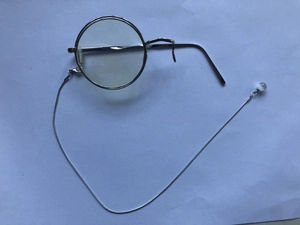 Macro detail of silver single-frame monocle with chain and catseye stone bead
