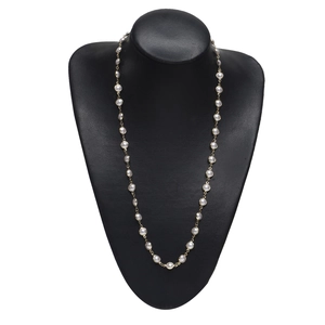 Collier élégant en chaîne dorée avec perles blanches sur un présentoir de bijoux noir