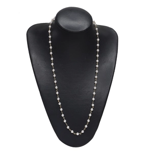 Elegante catena per occhiali con perle bianche e maglie dorate su un busto nero