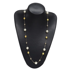 Détail d'un long collier avec perles blanches et perles dorées texturées sur un buste