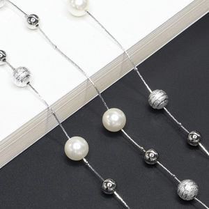 Détail de chaîne argentée avec perles blanches, boules miroir et sphères en métal givré