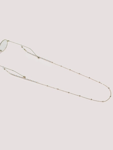 Detail of gold eyewear chain with small white and blue beads and silicone grips