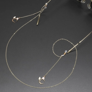 Golden non-slip metal eyewear chain featuring crown, moon and wings charm on black background